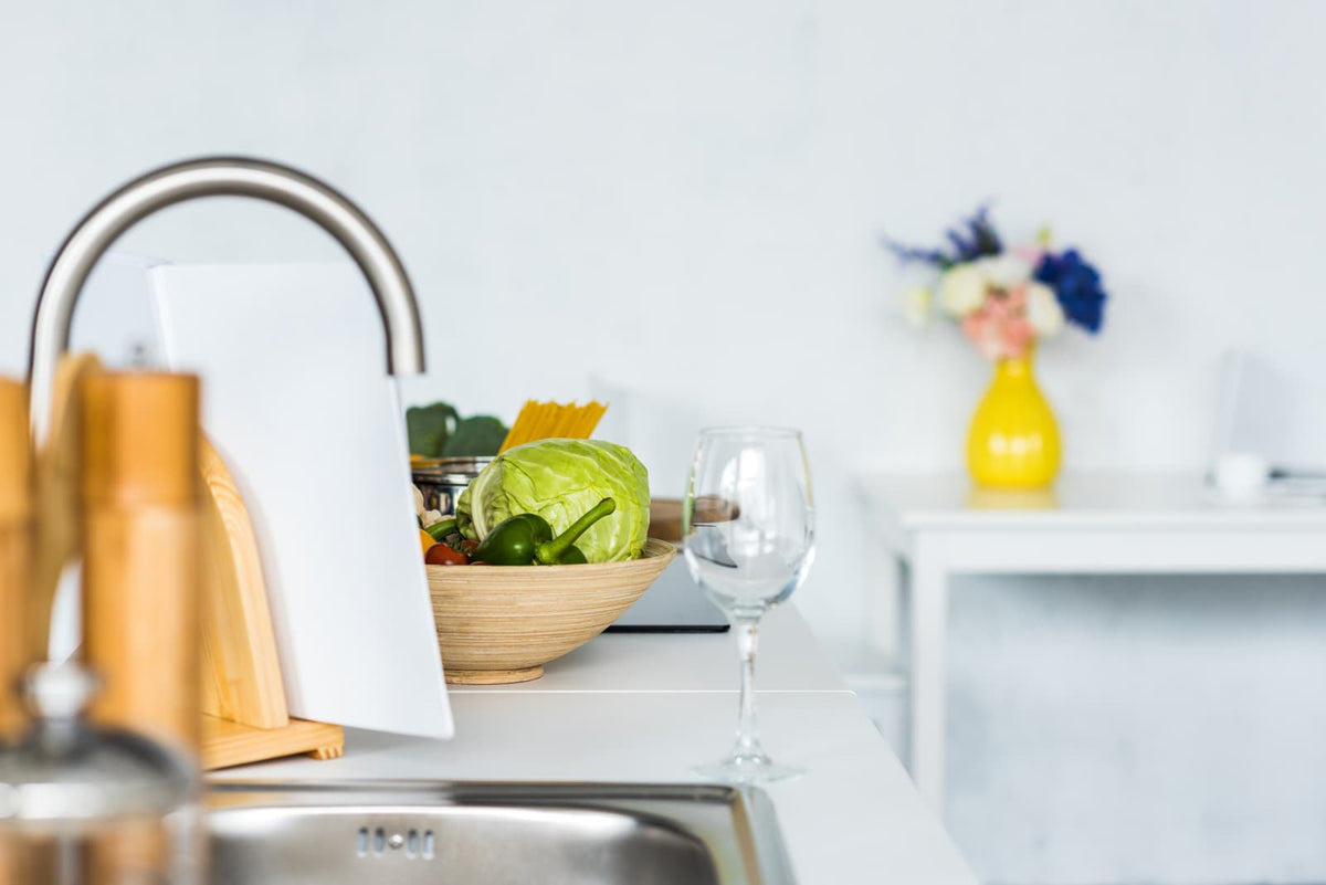 Modernes Küchenbecken mit Wasserhahn und Trinkglas auf der Arbeitsplatte.
