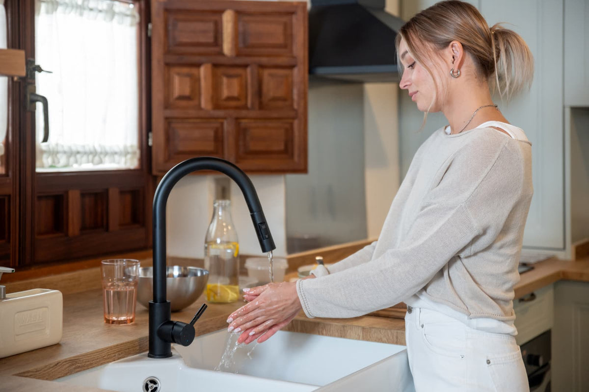 Frau wäscht sich die Hände am Küchenwasserhahn, um auf mögliches Kupfer im hauseigenen Trinkwasser hinzuweisen.