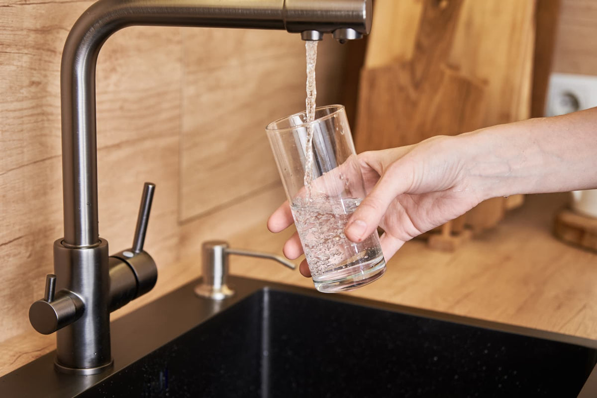Leitungswasser wird in einer modernen Küche in ein Glas gefüllt.