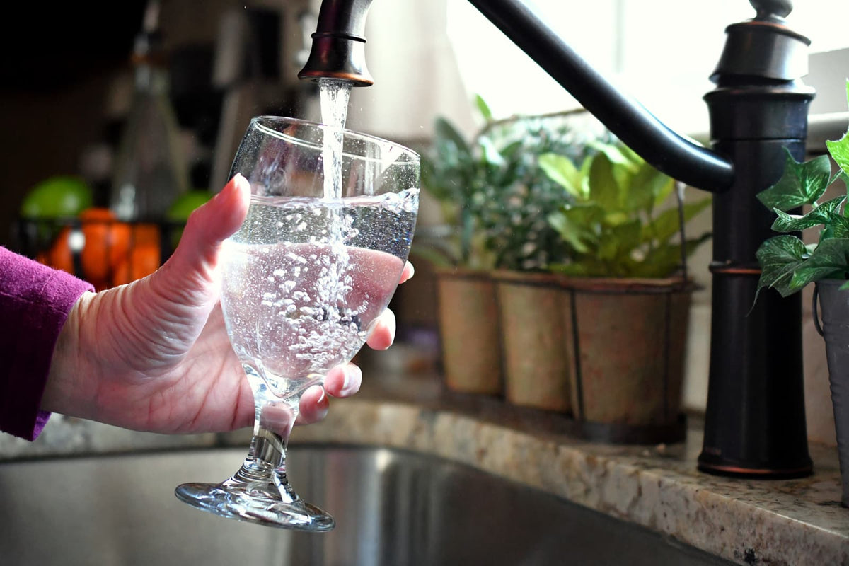 Küchenarmatur an einer modernen Spüle mit einem Glas Trinkwasser.