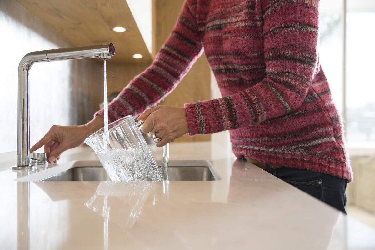 Glas Trinkwasser an einer modernen Küchenspüle im Haushalt.