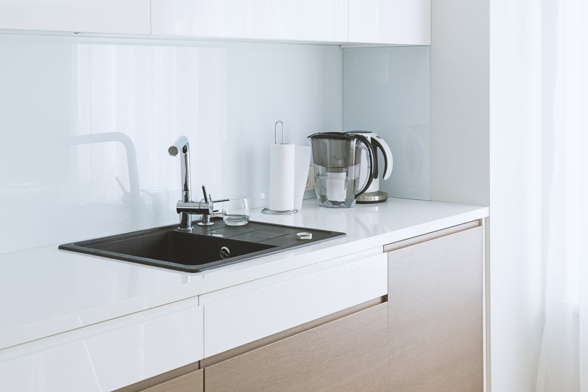 Moderne Küchenspüle mit Armatur und Trinkwasser auf der Arbeitsplatte.