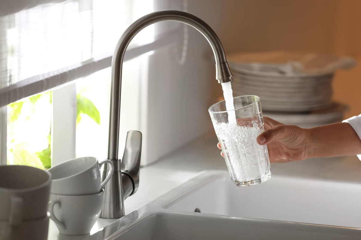 Wasser läuft aus einem Küchenhahn in ein Glas in einer modernen Küche.